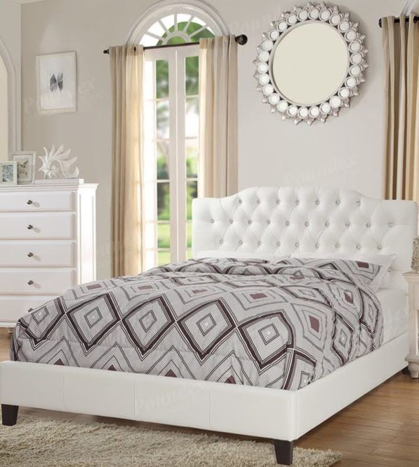 Elegant bedroom with a tufted white bed, geometric bedding, mirror, and dresser.